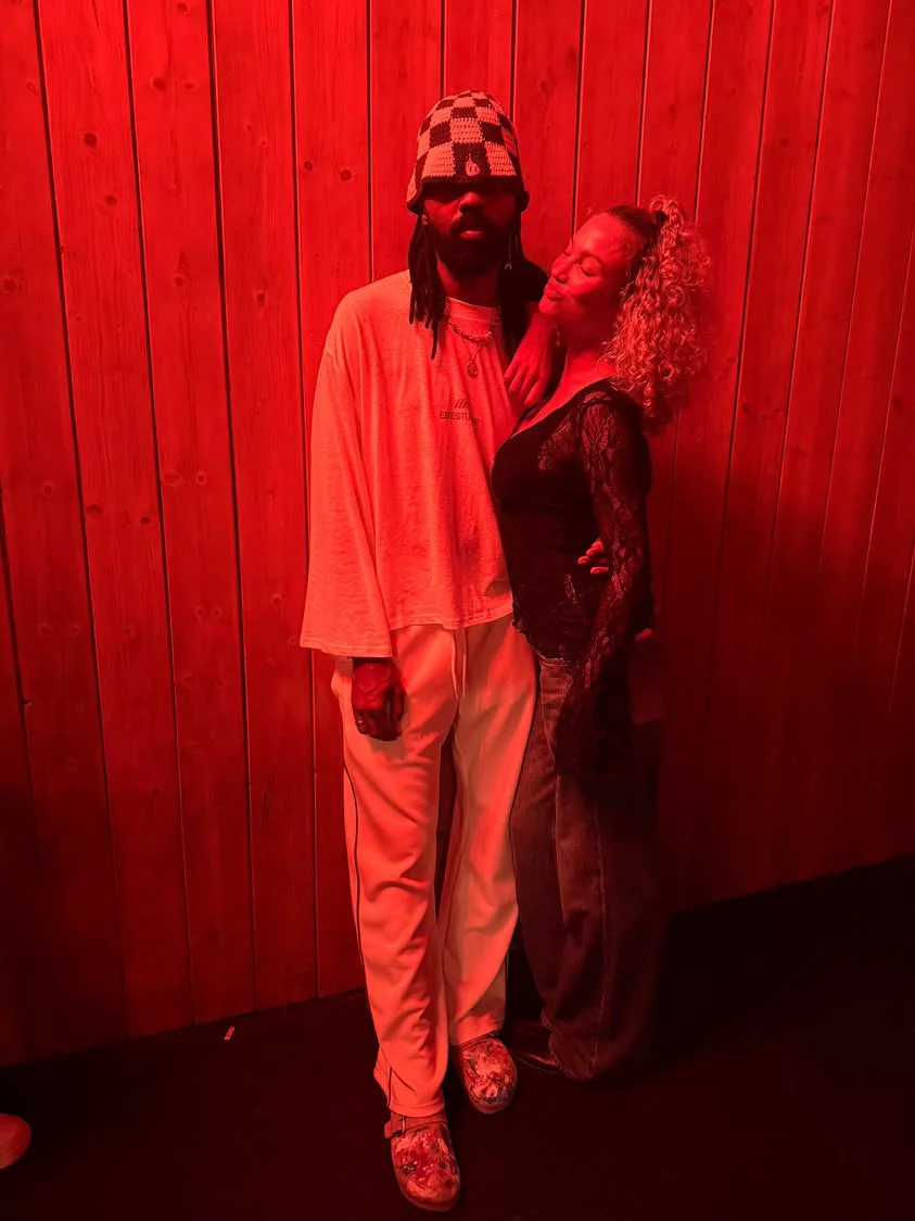 Two people in red light, one wearing a KAWAXX checked bucket hat